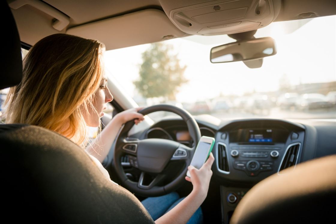 A person in a car looking at her phone

Description automatically generated